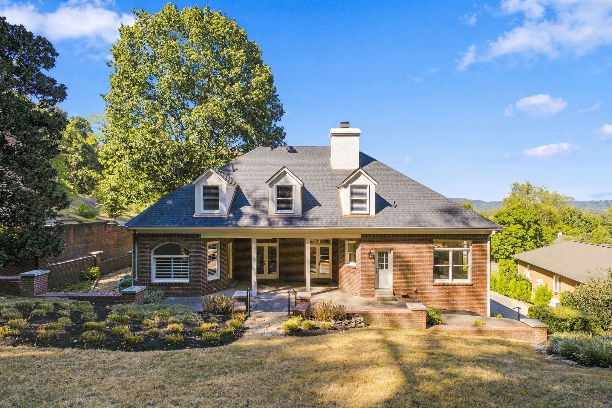 Rear exterior with the covered patio and wooded backdrop at 710 Ashley Run, Brentwood TN